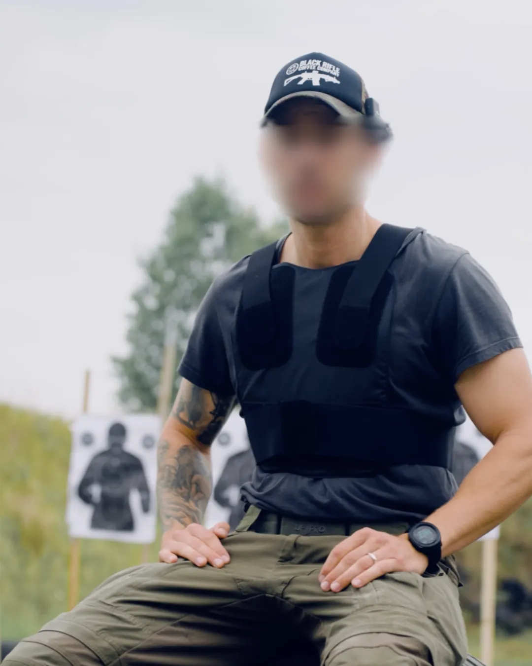 Person sitzt mit schwarzer VEP LITE über dem T-Shirt am Schießstand, Gesicht unkenntlich